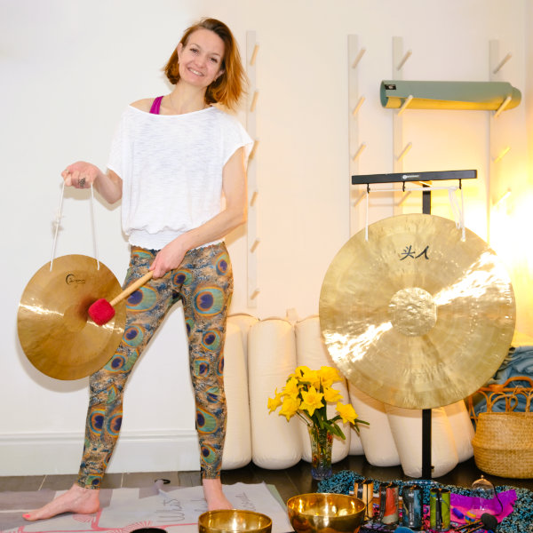 Fiona performing a Gong Bath with a large gong and singing bowls at a wellness event in Leeds